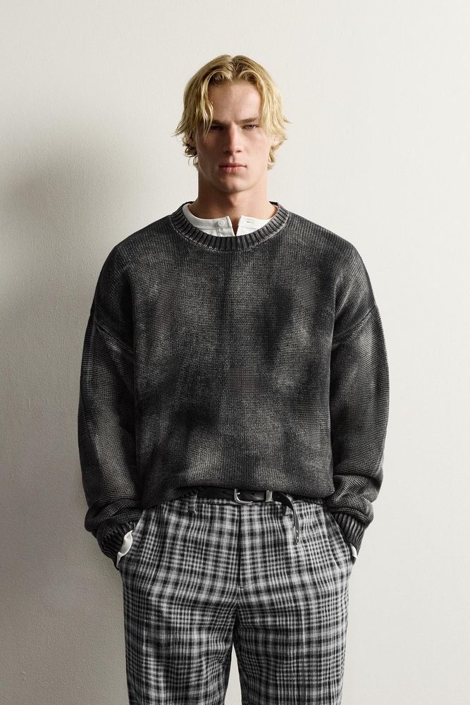 Dark relaxed crew-neck sweater with checked trousers.