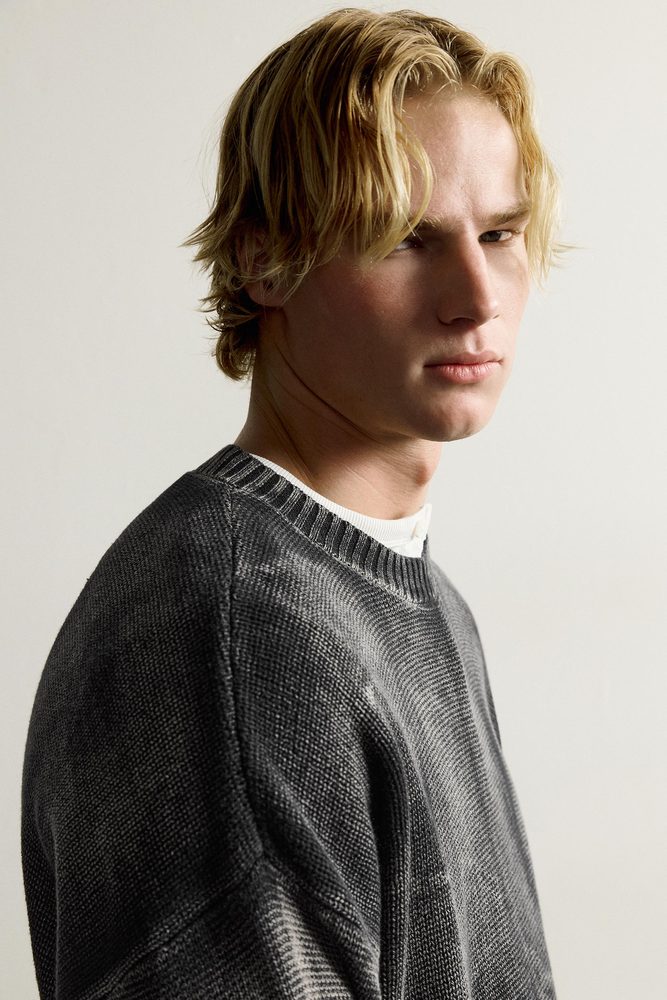 Dark crew-neck sweater, shoulder and neckline detail.