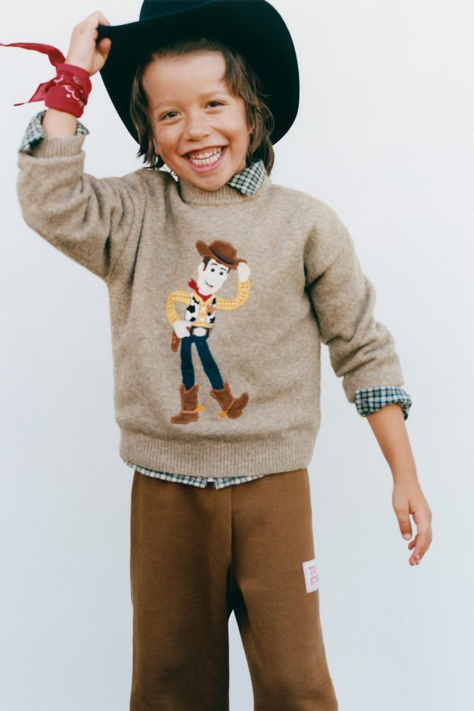 Child wearing a taupe graphic sweater.