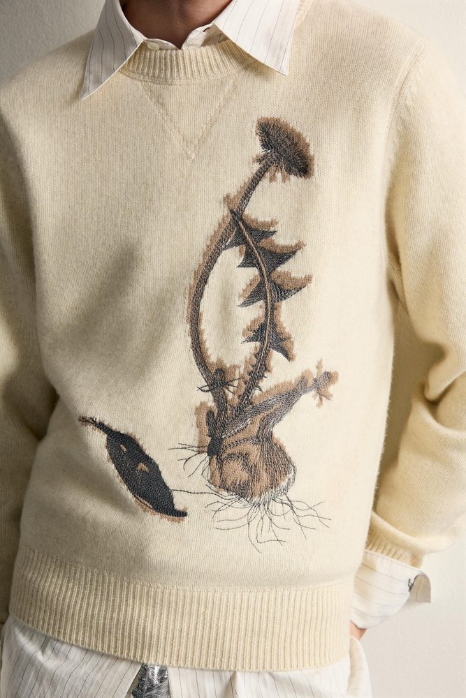 Cream sweater with a knitted decorative motif, close-up.