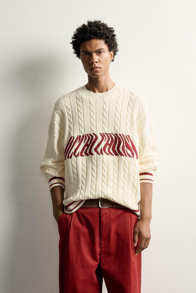 Cream cable sweater with red graphic accents.