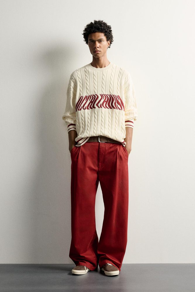 Cream cable sweater styled with red trousers.