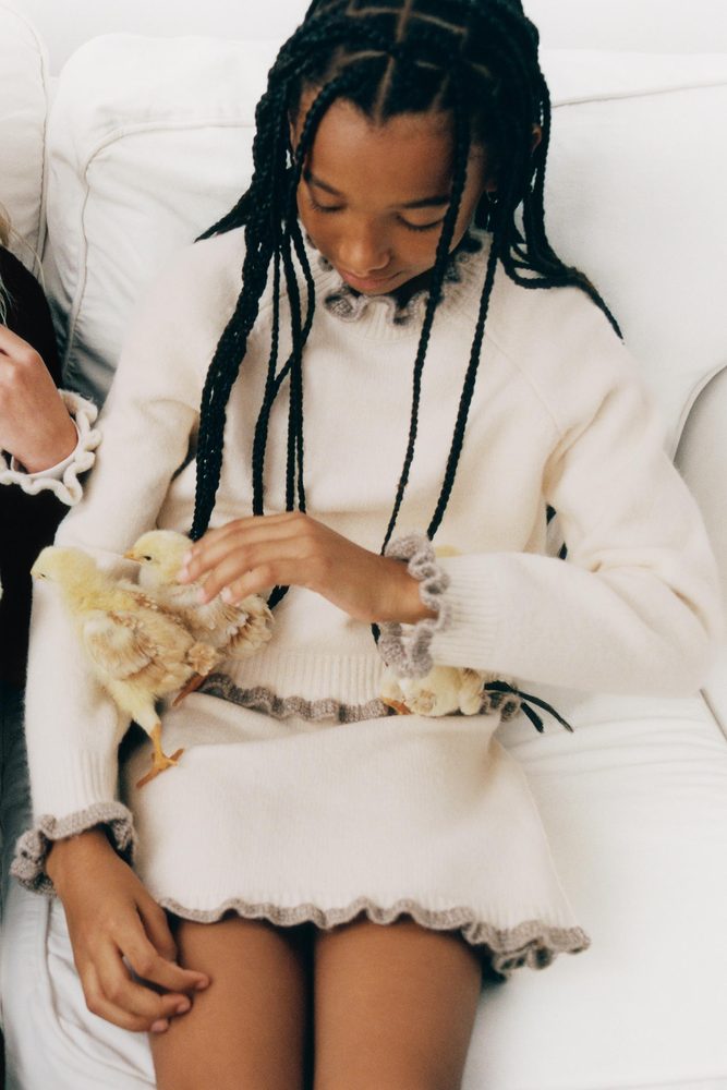 Cream knitted outfit with fringed edges.