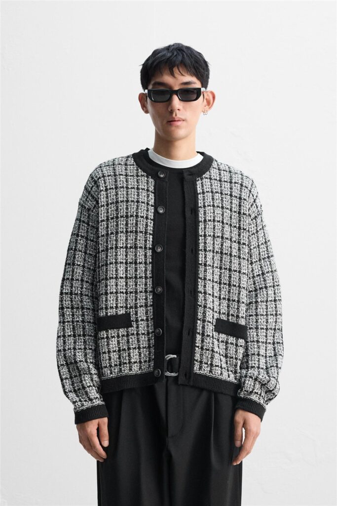 Male model wearing a black-and-white textured knit cardigan with contrast trim.